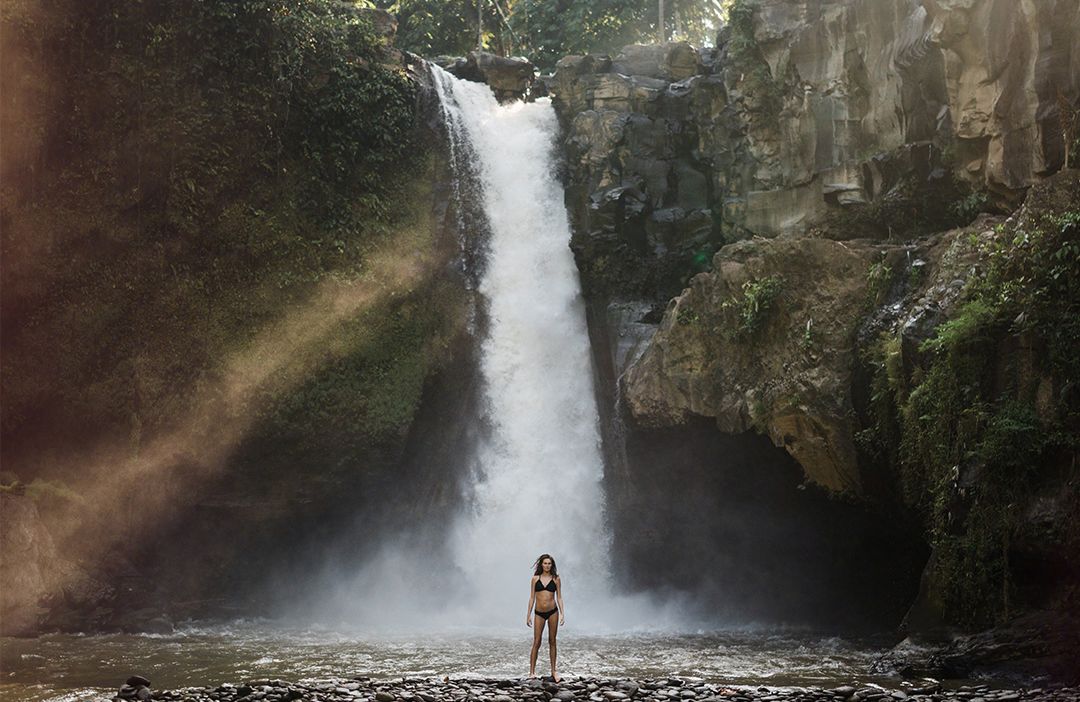20190404_bali-waterfall Woman standing under a waterfall