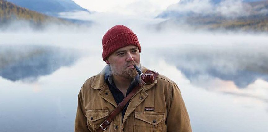 Andy smoking a pipe in front of a foggy lake